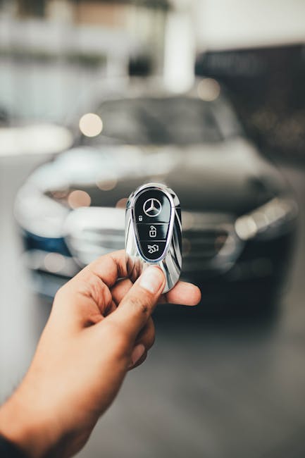 Close-up shot of a hand holding a car key with a blurred luxury car background, adding a premium feel.